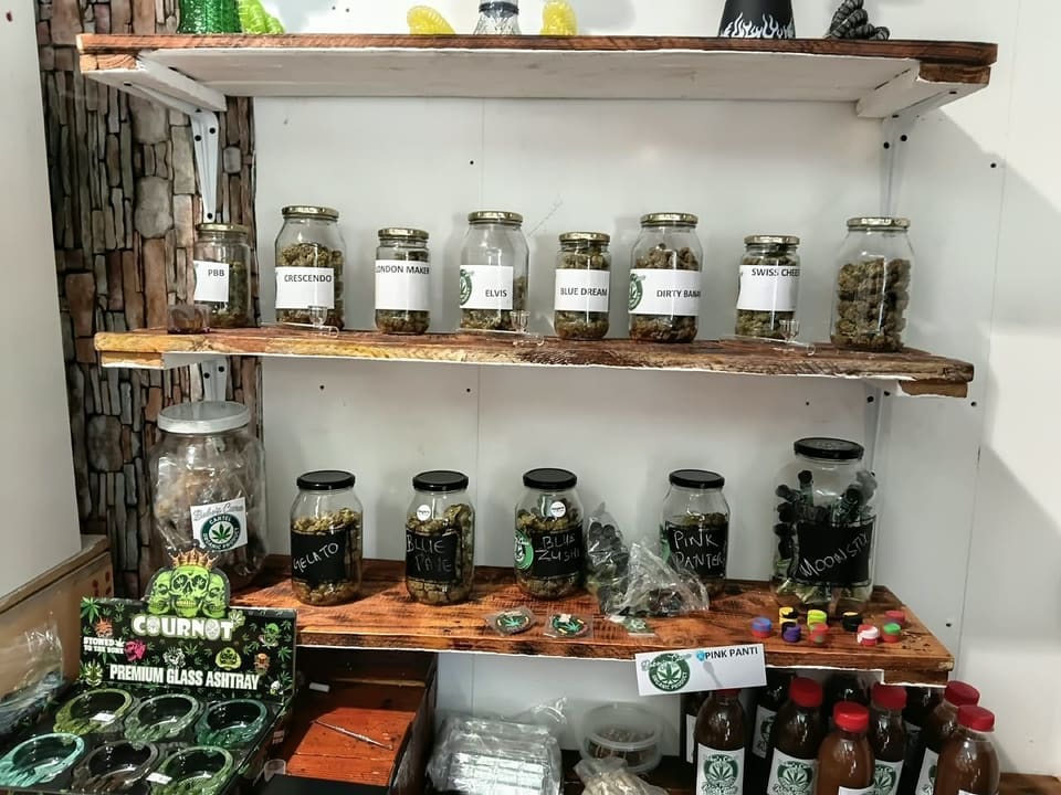 Close-up of labelled glass jars of dried herb on the shop's wooden shelf